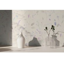 Vliesbehang met weidebloemenpatroon in paars en blauw op een lichte ondergrond, interieurvoorbeeld met vazen.