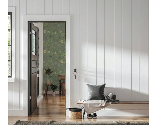 Hal met witte houten wandpanelen, houten bank en een open deur naar een kamer met groen behang met palmboommotief.