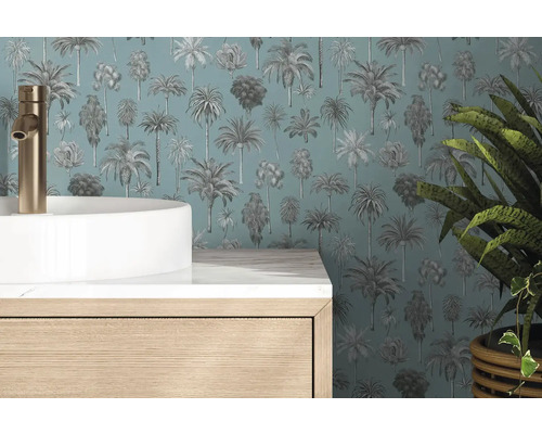 Behang met palmboompatroon achter een witte waskom met goudkleurige kraan en een houten onderkast in een moderne badkamer.