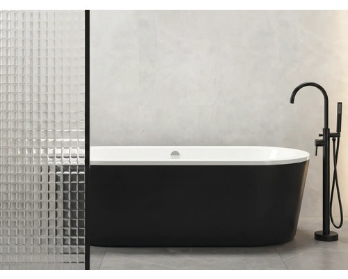 Vrijstaand bad met zwarte buitenkant en witte binnenkant naast armatuur in de badkamer.