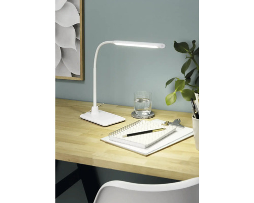 Bureau met bureaulamp, notitieblok, pen en glas water voor een heldere en georganiseerde werksfeer.