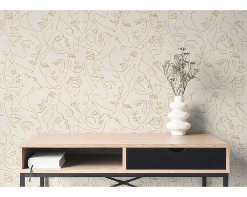 Vlies fotobehang met goudkleurig line art gezichtspatroon op een muur achter een houten consoletafel met een witte vaas.