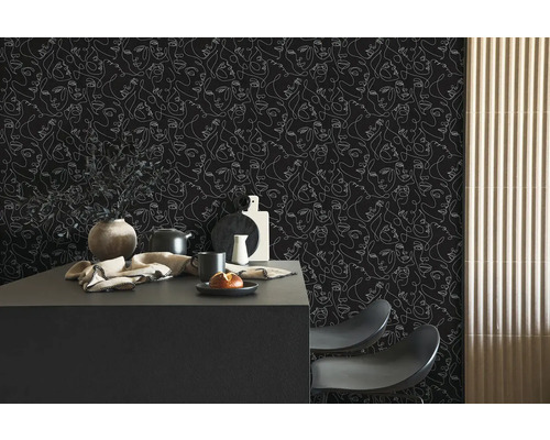 Donker behang met witte lijntekening van gezichten in een moderne keuken met een zwart kookeiland.