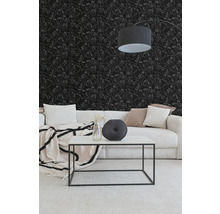 Woonkamer met zwart behang met witte gezichten in lijntekening, een lichte corduroy bank en een witte salontafel met een zwart metalen frame.