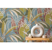 Vliesbehang met groot bladpatroon in blauw, groen en bruin achter houten sidetable met ronde witte vaas.