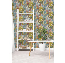 Vliesbehang met botanisch bladpatroon in groen en bruin op blauwe achtergrond, witte stellingkast en houten tafel in een lichte kamer.