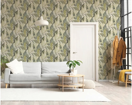 Lichte woonkamer met vliesbehang met bladpatroon, witte bank, ronde houten salontafel en een witte deur.