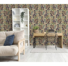 Woonkamer met botanisch behang met bladpatroon, een witte kast, een houten bureau met rotan stoel en een bank in lichte tinten.