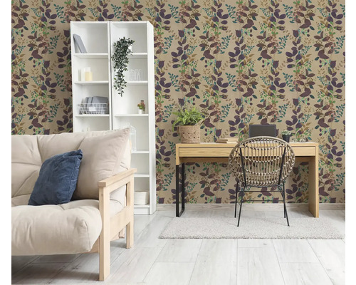 Woonkamer met botanisch behang met bladpatroon, een witte kast, een houten bureau met rotan stoel en een bank in lichte tinten.