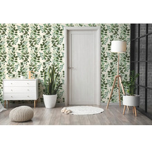 Lichte kamer met botanisch behang, witte ladekast, houten lampvoet en lichte binnendeur.