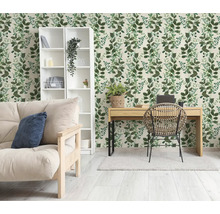 Lichte kamer met botanisch behang met groen bladpatroon, houten bureau, rotan stoel en witte boekenkast.