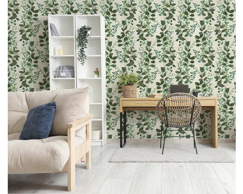 Lichte kamer met botanisch behang met groen bladpatroon, houten bureau, rotan stoel en witte boekenkast.