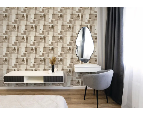 Slaapkamer met vliesbehang met architectuurpatroon in beige, moderne fauteuil, wit dressoir en asymmetrische spiegel.
