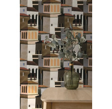 Behang met grafisch patroon van mediterrane huizen en torens, getoond achter een houten tafel en een glazen vaas met takken.