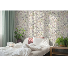 Lichte slaapkamer met een kat op het witte bed, bloemenbehang in botanische stijl, groene gordijnen en kamerplanten.