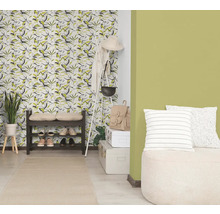 Heldere hal met behang met bladmotief, groene muurverf, donker schoenenrek, witte kapstok en een licht vloerkleed.