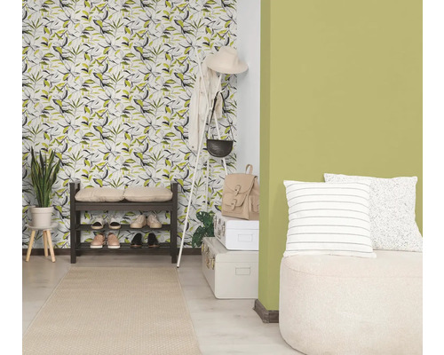 Heldere hal met behang met bladmotief, groene muurverf, donker schoenenrek, witte kapstok en een licht vloerkleed.