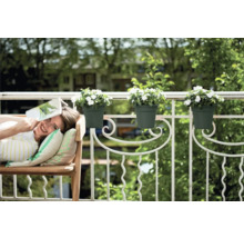 Vrouw ontspant op het balkon met bloembakken aan de reling