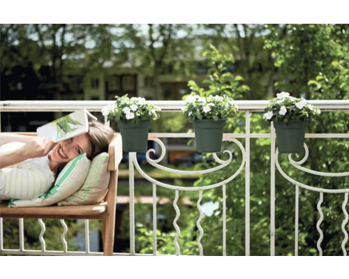 Vrouw ontspant op het balkon met bloembakken aan de reling