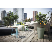 Een dakterras met een zithoek, een tafel, planten en uitzicht op de stad.