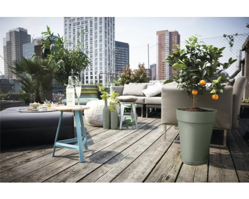 Een dakterras met een zithoek, een tafel, planten en uitzicht op de stad.