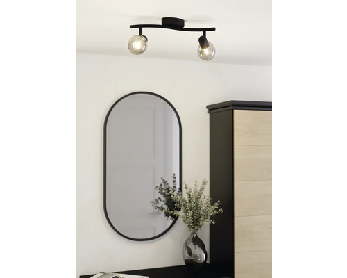 Plafondlamp met twee spots en ovale spiegel boven ladekast