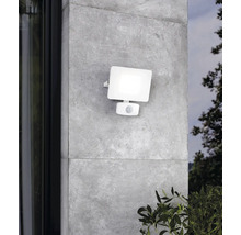 Witte buitenlamp met bewegingssensor aan een grijze muur