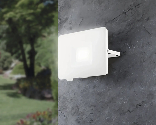 Witte led buitenlamp aan een muur naast een tuin