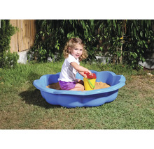 Meisje speelt in een blauwe zandbak met zandspeelgoed in de tuin.