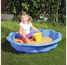 Kind speelt in een blauwe zandbak met zandspeelgoed in de tuin