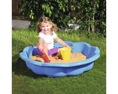 Kind speelt in een blauwe zandbak met zandspeelgoed in de tuin