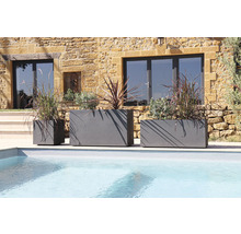 Drie grijze plantenbakken van verschillende grootte bij het zwembad