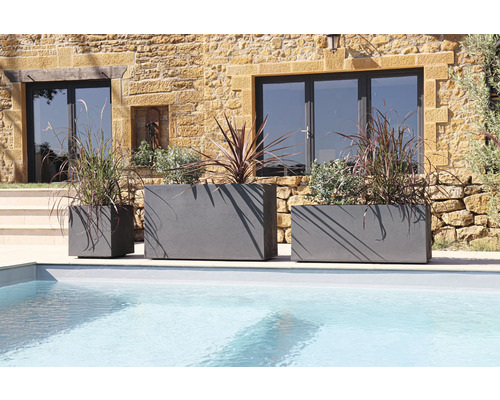 Drie grijze plantenbakken van verschillende grootte bij het zwembad