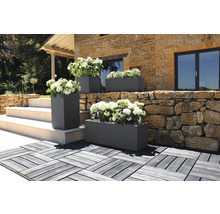 Buitenshot van rechthoekige en vierkante plantenbakken met bloemen voor een gebouw.