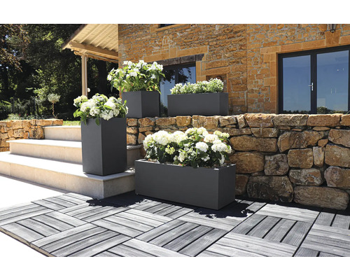 Buitenshot van rechthoekige en vierkante plantenbakken met bloemen voor een gebouw.