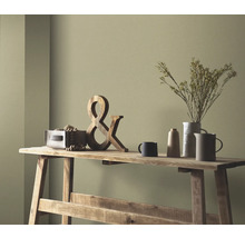 Decoratieve scène op een houten tafel met houten decoratie, droogbloemen in een vaas en keramisch servies voor een gekleurde wand.