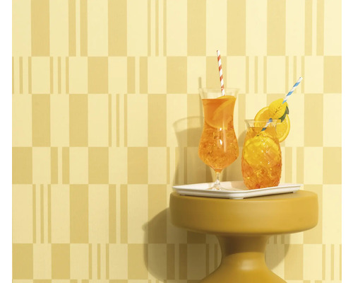 Twee drankjes met rietjes en sinaasappelschijfjes op een klein tafeltje voor een wand met patroon.