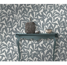 Decoratief interieur met een tafel, lantaarn en een muur met bladmotief behang.