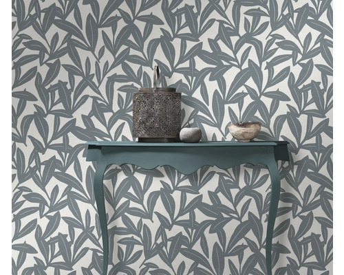 Decoratief interieur met een tafel, lantaarn en een muur met bladmotief behang.