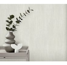 Close-up van een gestructureerd, lichtgekleurd behang met een vaas met planten op een tafel