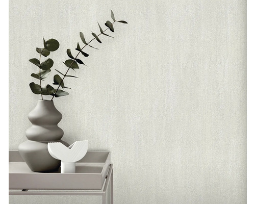 Close-up van een gestructureerd, lichtgekleurd behang met een vaas met planten op een tafel