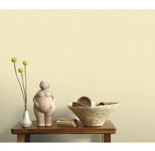 Decoratief arrangement op een houten tafel voor een behang met textielpatroon.