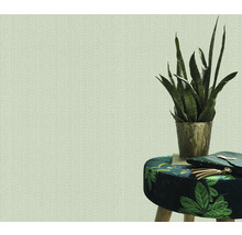 Lichtkleurig behang met visgraatmotief naast een kruk met bladmotief en een kamerplant