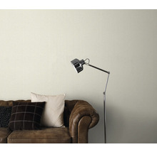 Behang met patroon boven een bruine leren bank met staande lamp