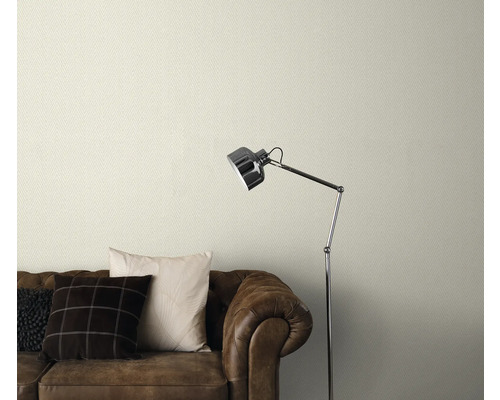 Behang met patroon boven een bruine leren bank met staande lamp