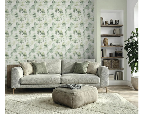 Woonkamer met bank, hocker, vloerkleed, boekenplank en behang met boommotief voor een gezellige sfeer