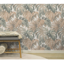 Kamer met een patroonbehang met tropische bladeren, een bank met kussen en een opgerolde deken.