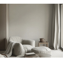 Woonkamer met fauteuil, voetenbank, bijzettafel, gordijn en decoratie voor een lichte en vriendelijke sfeer.