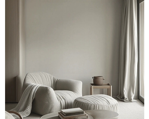 Woonkamer met fauteuil, voetenbank, bijzettafel, gordijn en decoratie voor een lichte en vriendelijke sfeer.