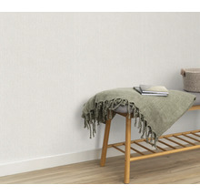 Scene met licht vliesbehang, bank met plank, deken en boeken.